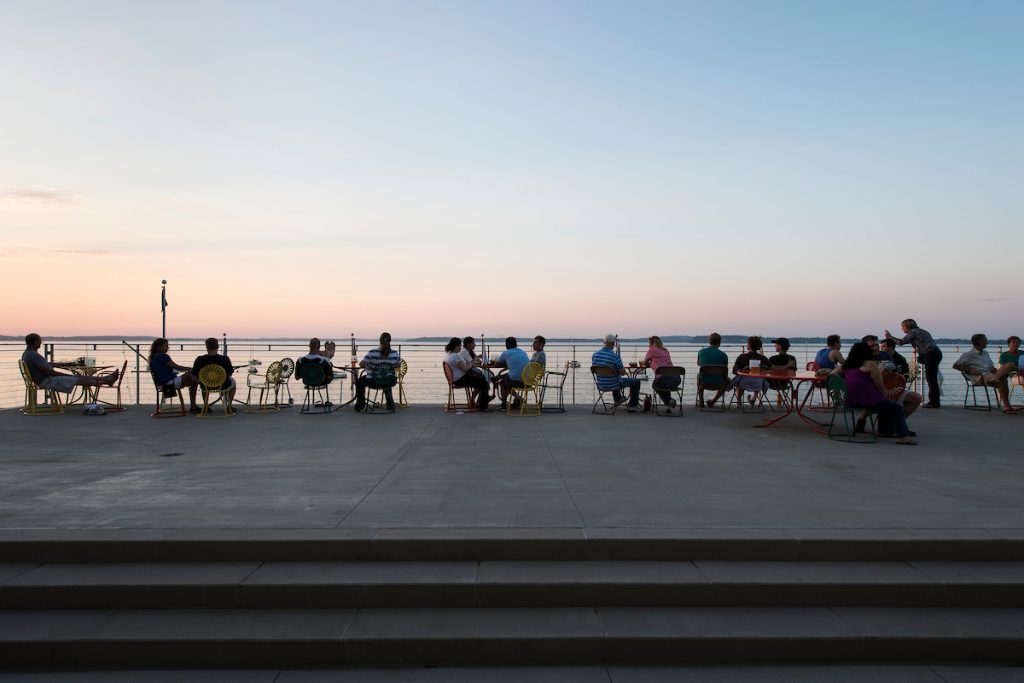 People relax in chairs on the upper deck of the Wisconsin Union Theater's Shannon Sunset Lounge as the sun sets over Lake Mendota and the Memorial Union Terrace at the University of Wisconsin-Madison during a summer evening on July 26, 2014. (Photo by Jeff Miller/UW-Madison)